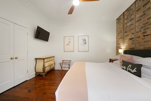 Un dormitorio con una cama grande, un aparador, un televisor y obras de arte en la pared.