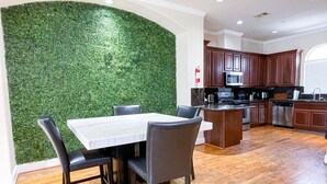 A modern kitchen with wooden cabinets, a marble countertop, and a green wall. - Immersive Themed Stay | Space, Jungle & Greek-Inspired Getaway! (Houston)