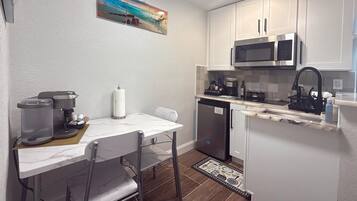 A compact kitchen with a coffee maker, microwave, and dishwasher.