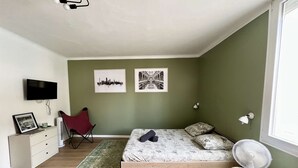 Ein Schlafzimmer mit einem Bett, einem Sessel, einem Fernseher und zwei Wandlampen.