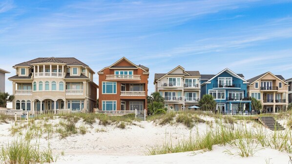 A beachfront property with multiple houses, a sandy beach, and a clear sky.