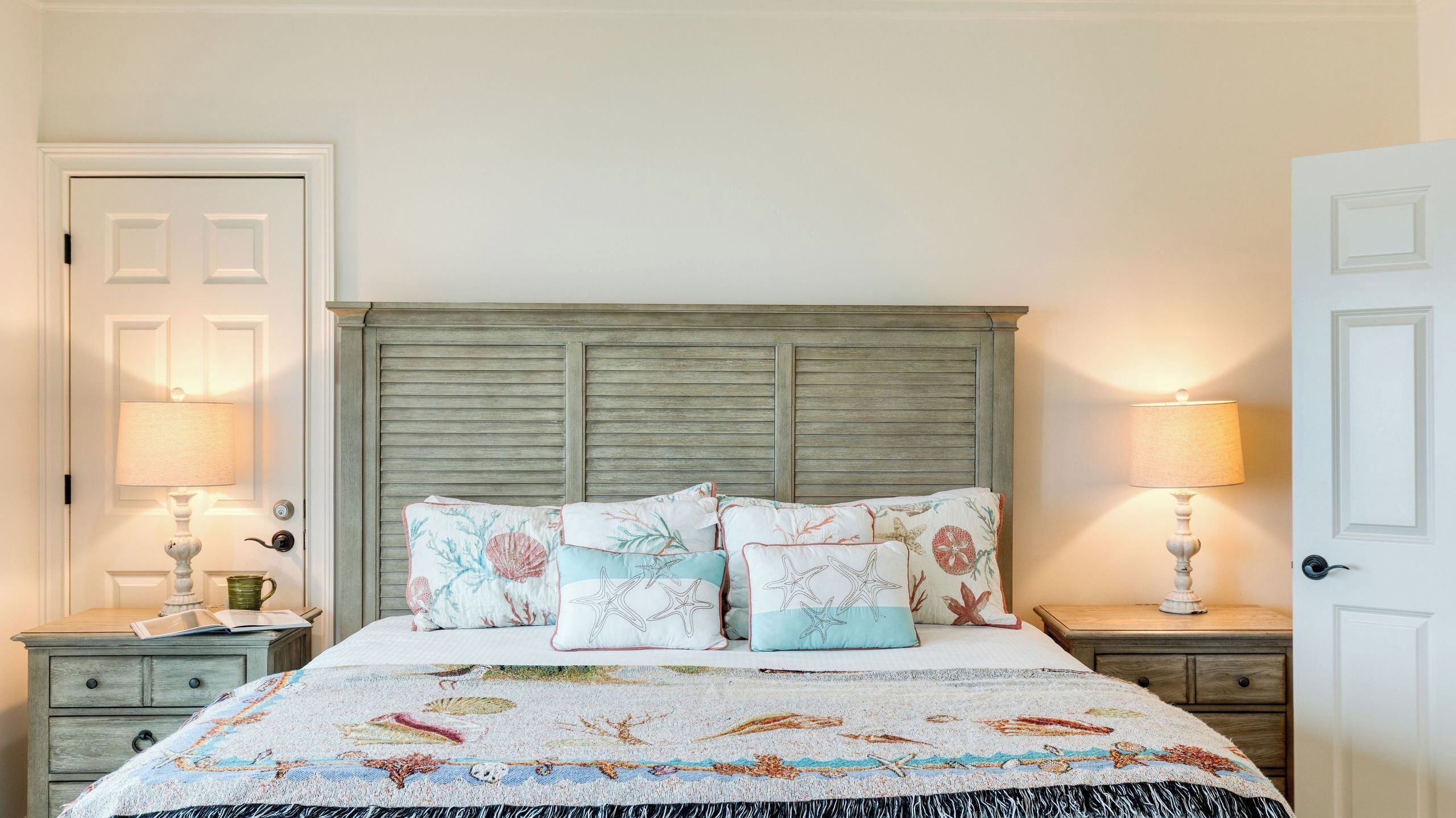 A bedroom with a bed, two nightstands, a wooden headboard, and two wall-mounted lamps.