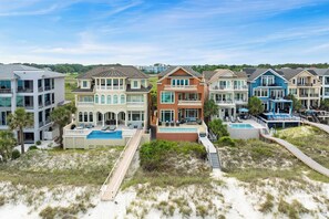 A beachfront property with multiple houses, a swimming pool, and a boardwalk.