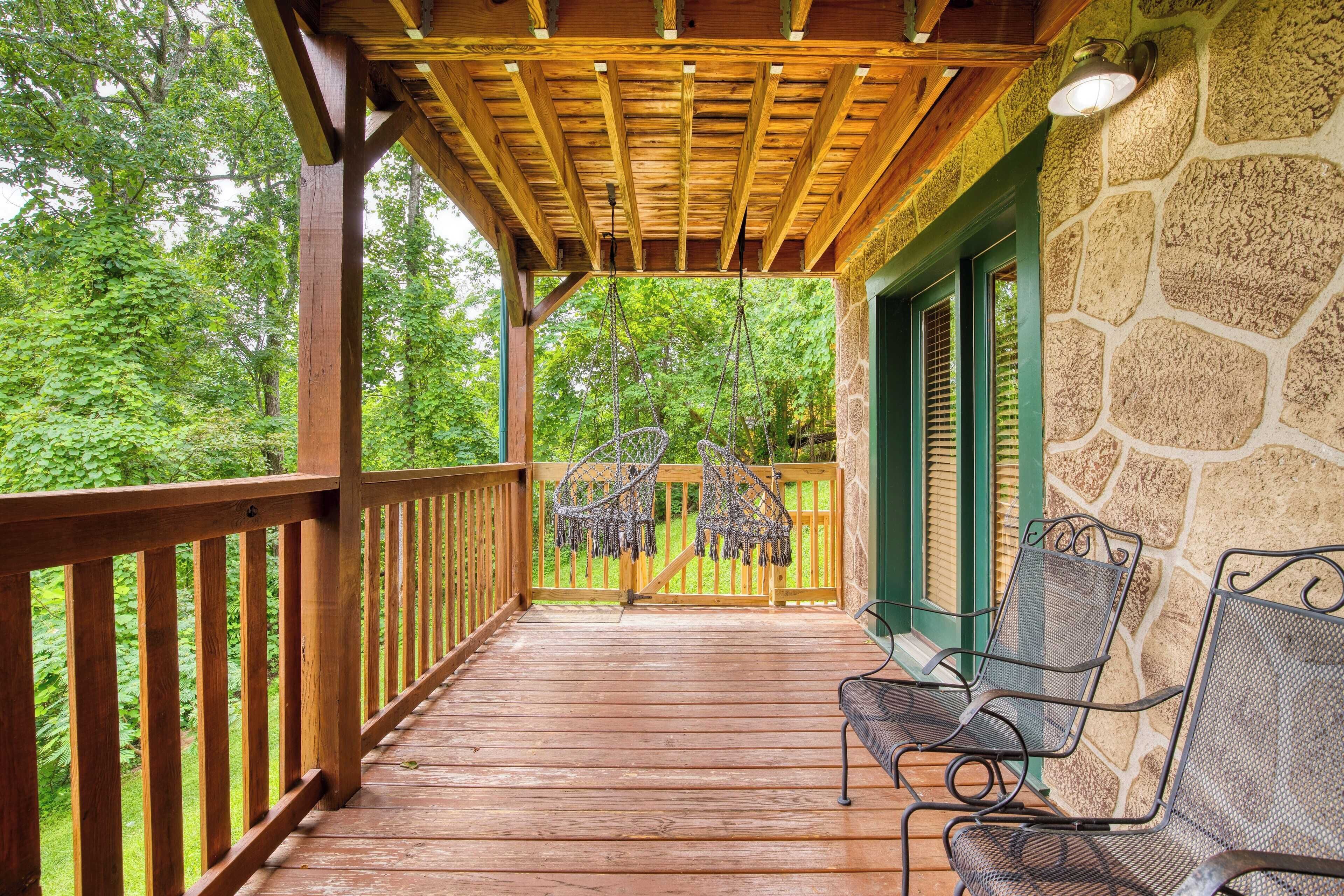 A wooden deck with a stone wall and a hanging chair.