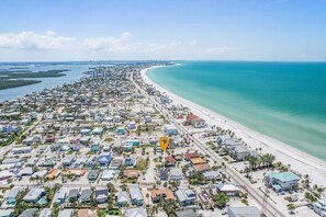 Vue aérienne d’une zone résidentielle côtière, avec une plage, des maisons et un point de repère clairement identifiable.