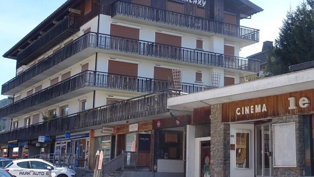 A multi-story building with balconies, a cinema, and a restaurant named 'petitpois'. - Central studio in Les Gets for 2 with Wifi (Les Gets)