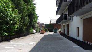 A quiet street with a row of modern buildings, a clear sky, and a green tree-lined sidewalk. - Central studio in Les Gets for 2 with Wifi (Les Gets)