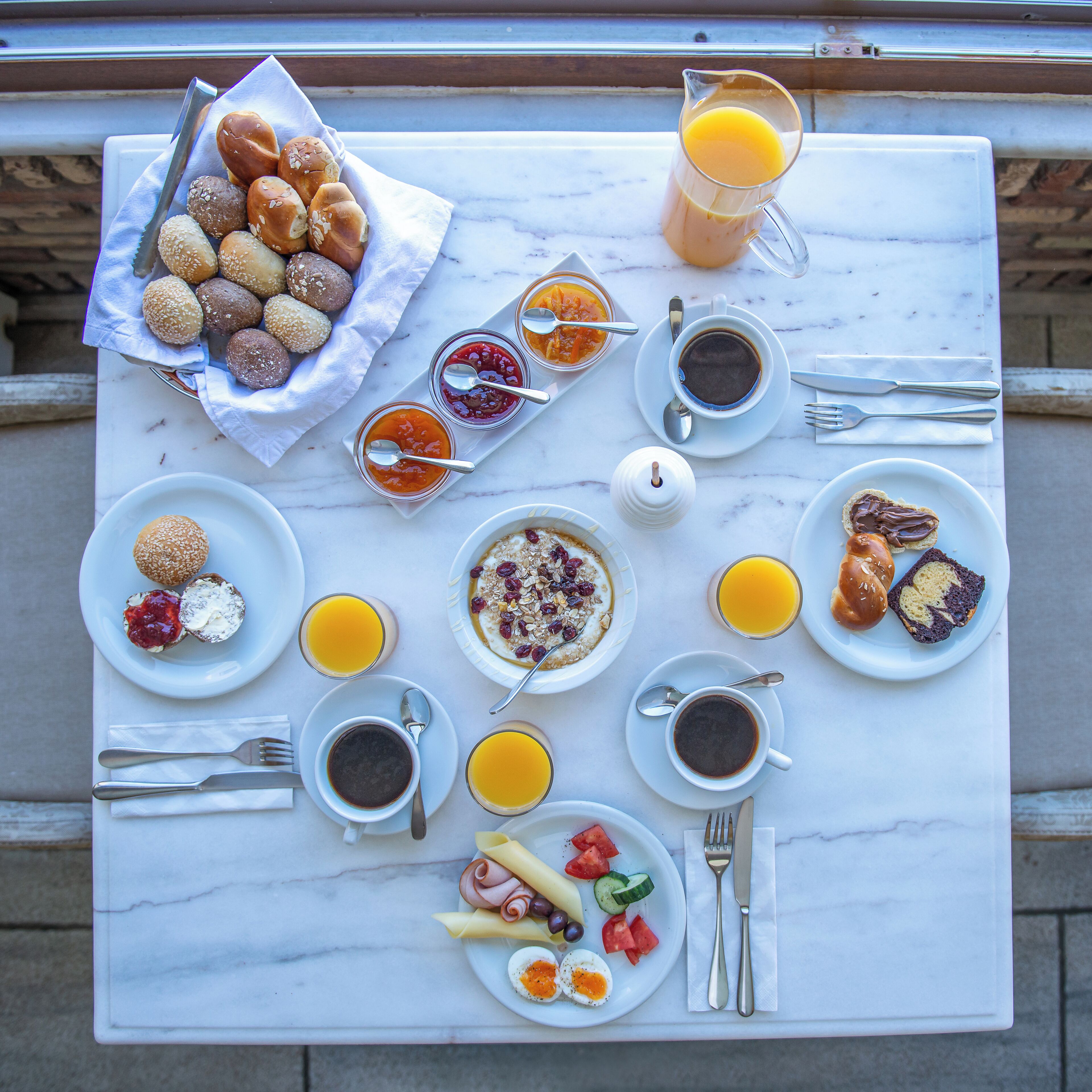 Ein reichhaltiges Frühstücksbuffet auf einer Marmortischplatte mit verschiedenen Speisen und Getränken.