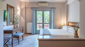 Une chambre à coucher avec un lit, une table de chevet et un bureau avec une chaise. Il y a une fenêtre avec des rideaux, un radiateur et une plante en pot.