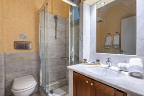 Une salle de bain moderne avec une douche à parois de verre, des toilettes, un lavabo avec un miroir et un porte-serviettes.