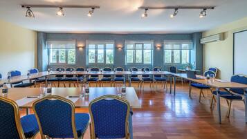 A conference room with long tables, chairs, and ceiling lights.