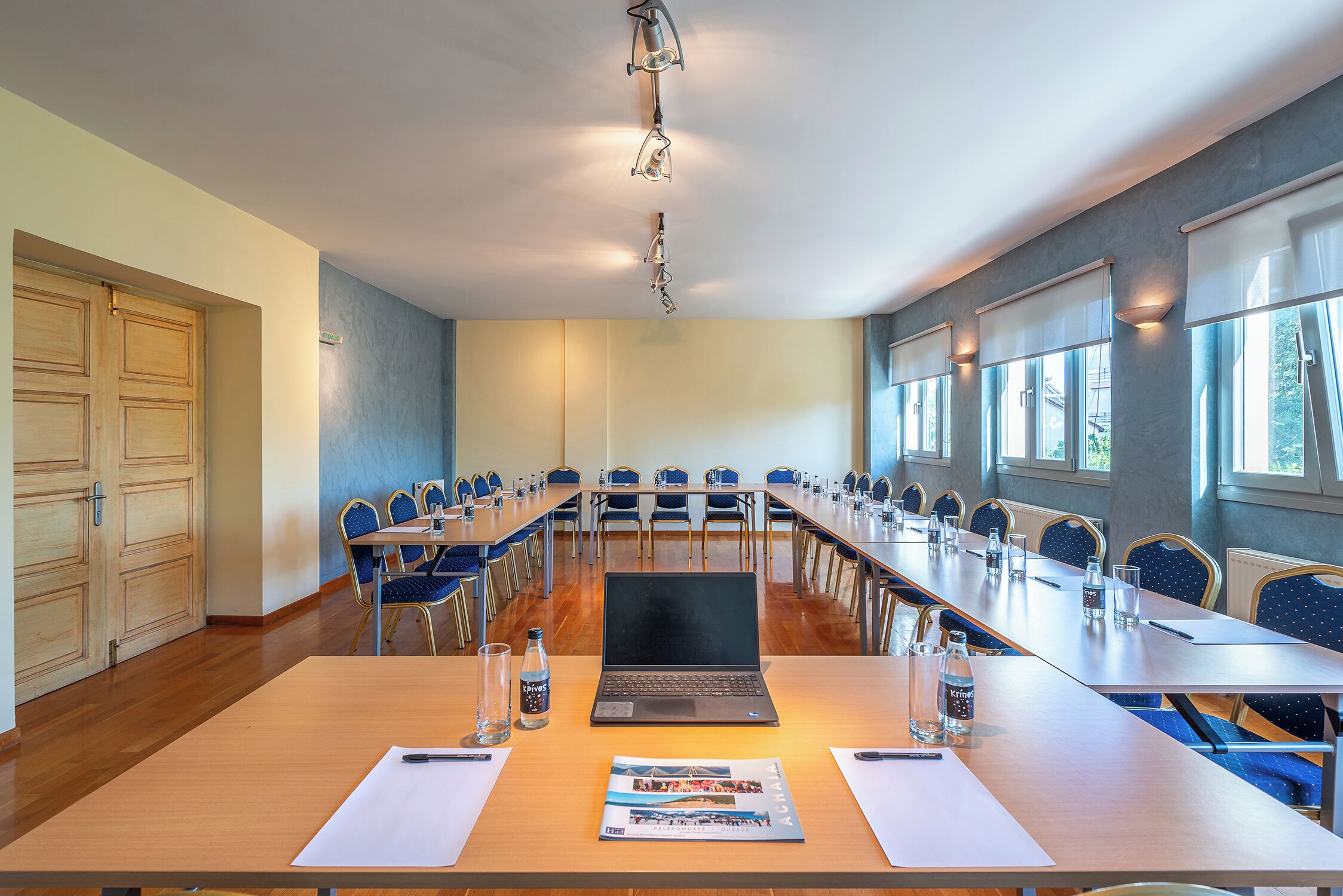 A conference room with a long table, chairs, a laptop, and a projector.