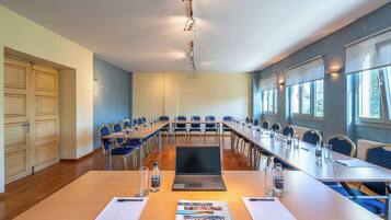A conference room with a long table, chairs, a laptop, and a projector.