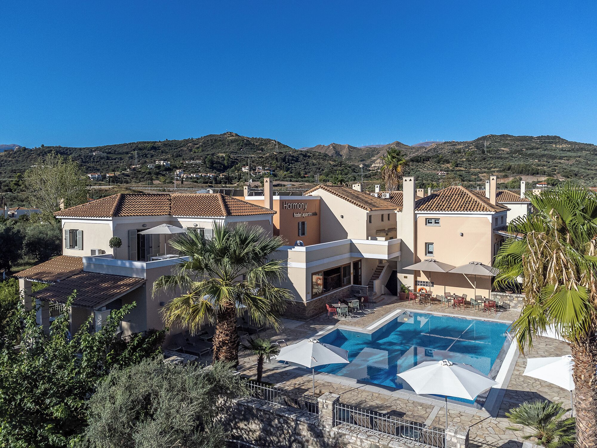 A hotel with a pool, outdoor seating, and a view of the surrounding hills.