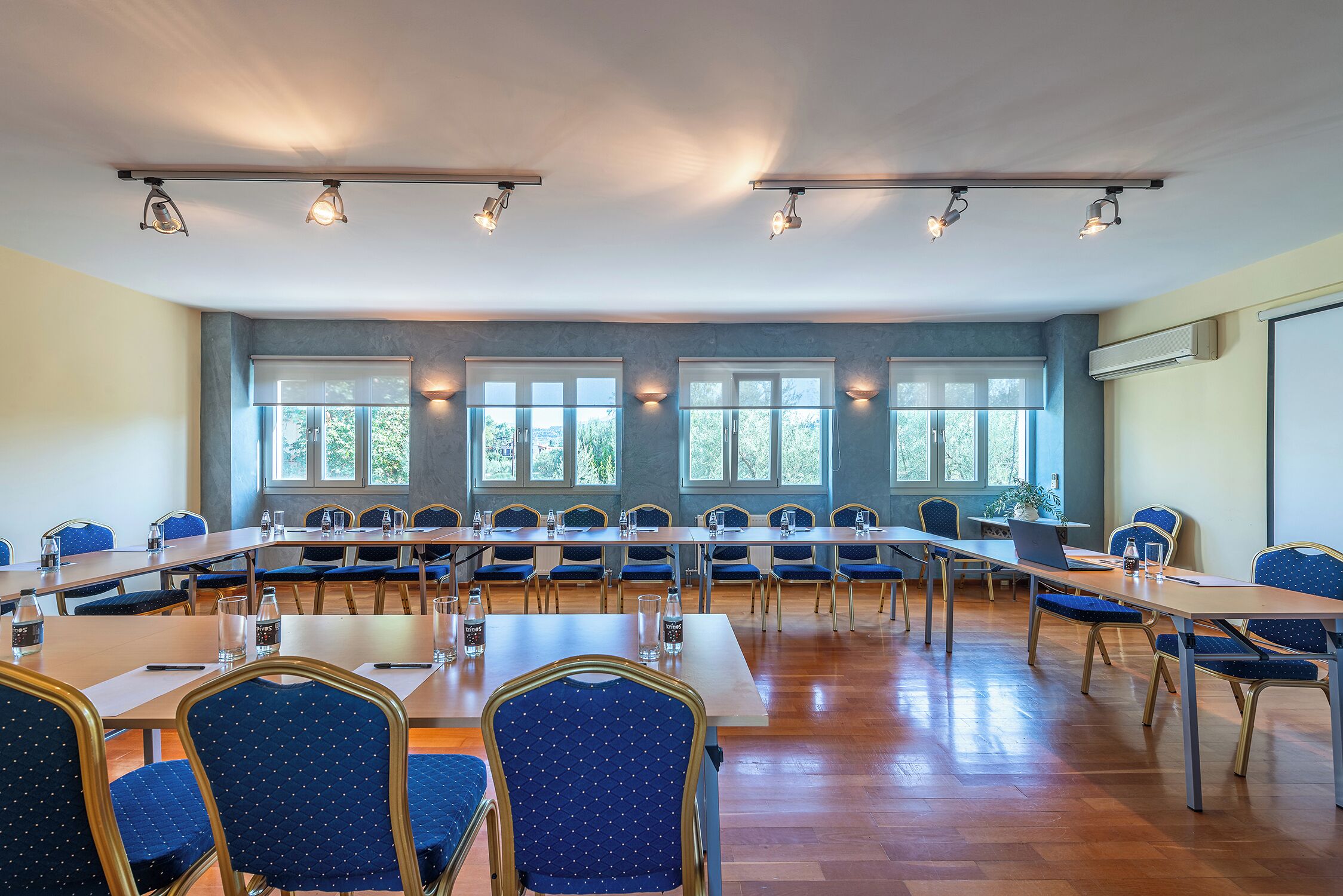 A conference room with long tables, chairs, and ceiling lights.
