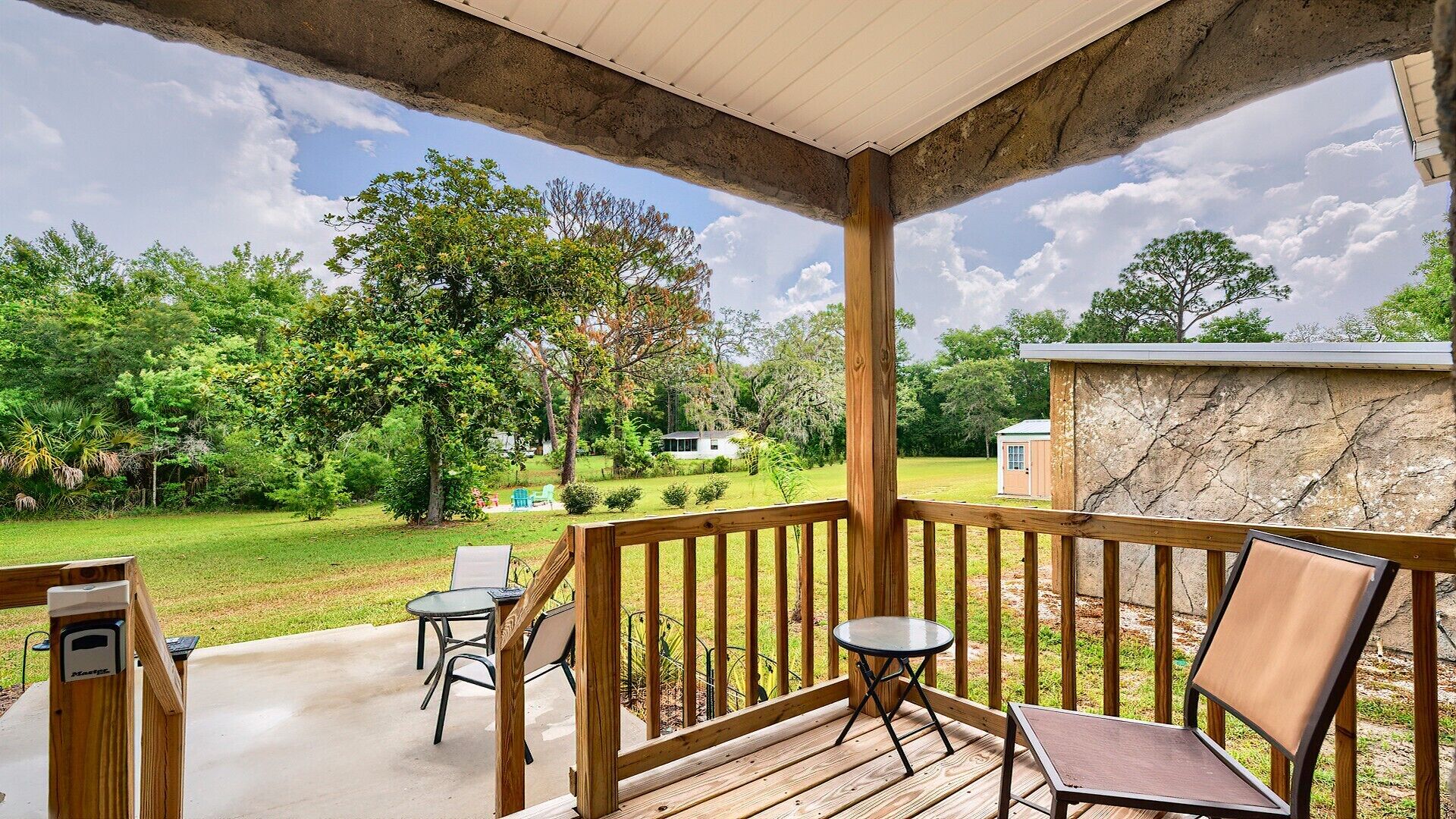 A covered outdoor deck with wooden railings, a table, and two chairs.