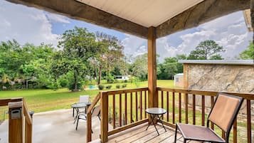 A covered outdoor deck with wooden railings, a table, and two chairs.