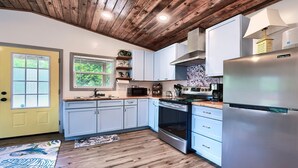 Una cocina moderna con armarios blancos, un refrigerador de acero inoxidable y piso de madera.