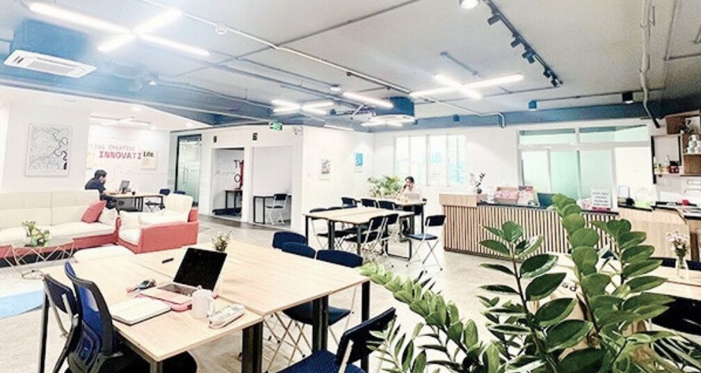 A modern office space with multiple workstations, a reception area, and a casual seating area.