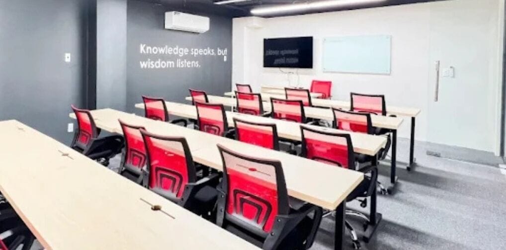 Ein Konferenzraum mit Tischen, Stühlen, einer Projektionsleinwand und einem motivierenden Zitat an der Wand.