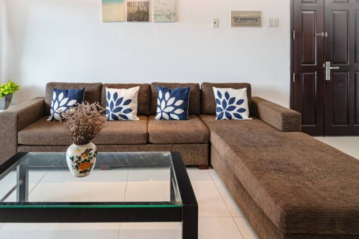 A living room with a brown sectional sofa, a glass coffee table, and decorative pillows.