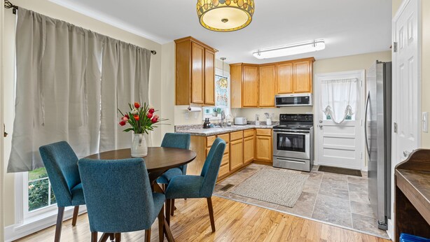 Una cocina moderna con armarios de madera, un refrigerador de acero inoxidable y un comedor con sillas azules y una mesa.