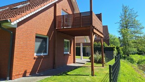Une maison en briques avec un balcon et une pelouse bien entretenue.