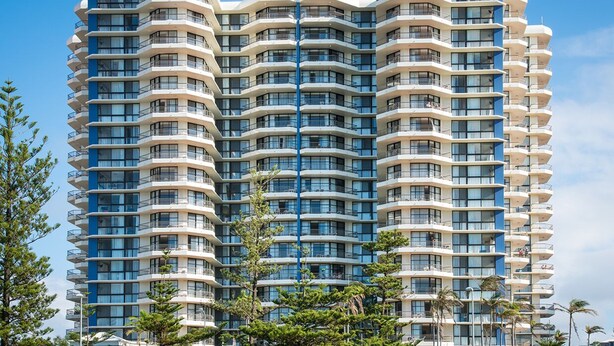 Un hotel de varios pisos con fachada curva, balcones en cada planta y un elemento vertical central.
