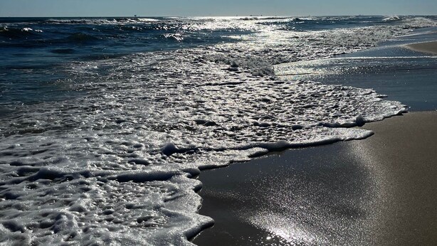 A beach with waves reaching the shore under a clear sky. - Bayfront Home with Beach Access (Gulf Shores)