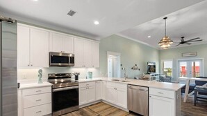 A modern kitchen with white cabinets, stainless steel appliances, and a wooden floor. - Bayfront Home with Beach Access (Gulf Shores)