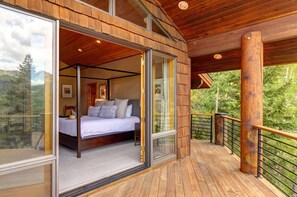 Een slaapkamer met een groot bed, een glazen deur naar een balkon en uitzicht op de omgeving.