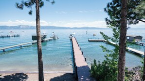 A clear view of a lake with a wooden dock extending into the water, surrounded by trees and boats anchored nearby.