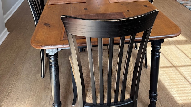 A dining area with a wooden table, black chairs, and a vase of pink flowers. - Pleasantly Charming 2-bedroom duplex in  Wynnton Village Historic District. (Columbus)
