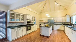 A spacious kitchen with white cabinetry, a central island, and a large window providing natural light. - Beautiful, Well-Appointed Villa With Excellent Staff and Magnificent Sea Views (Montego Bay)