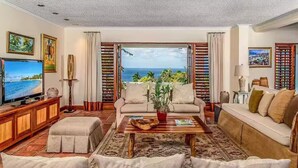 A living room with a television, sofas, a coffee table, and a view of the ocean. - Beautiful, Well-Appointed Villa With Excellent Staff and Magnificent Sea Views (Montego Bay)