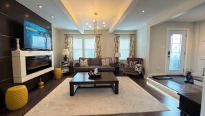 Una sala de estar moderna con chimenea, televisor, sofá, mesa de centro y candelabro.