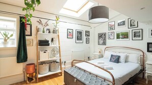 Een moderne slaapkamer met een bed, nachtkastjes, een kledingkast, een ventilator en een dakraam.