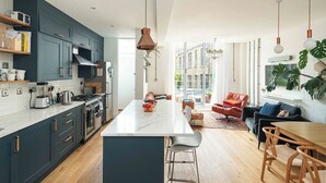 Een moderne keuken met donkere kastjes, een centraal eiland en een zithoek met een bank en stoelen.