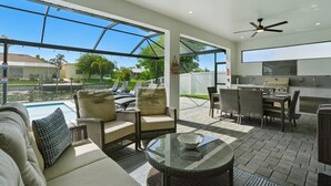 Un patio exterior con piscina, mobiliario y una parrilla.