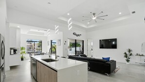 Una cocina moderna con una isla central, un sofá de cuero negro y un televisor de pantalla plana montado en la pared.