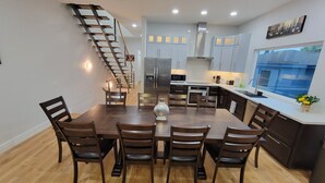 A modern kitchen with a central island, stainless steel appliances, and a staircase leading to an upper level.