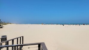 A wide sandy beach with a clear blue sky.