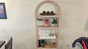 Une étagère en bois, dotée de plusieurs compartiments, comprenant une étagère supérieure où sont disposés des objets décoratifs, une étagère centrale où sont rangés des verres, et une étagère inférieure sur laquelle se trouve un plateau portant l’inscription « HOTTY TODDY ! ».