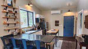 Una cocina moderna con una isla central, taburetes de bar y una puerta azul.