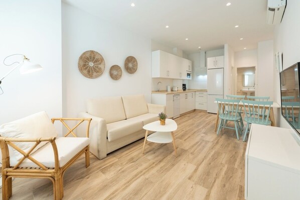 A modern living room with a sofa, a round table, and a dining area with chairs.