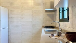 Une cuisine moderne avec un réfrigérateur blanc, un évier en acier inoxydable et un saladier en bois posé sur le plan de travail.