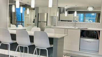 A modern kitchen with a central island, white chairs, and pendant lighting.