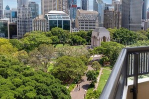 A park with a pathway surrounded by trees, set against a backdrop of modern high-rise buildings. - Stylish Family 1BR + Cozy Bunks for 5 with Games (Darlinghurst)