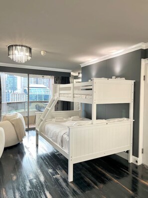 Une chambre moderne avec un lit superposé, une grande fenêtre donnant sur la ville et un lustre.