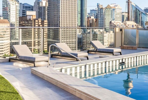 Ein Pool auf dem Dach mit Liegestühlen und Blick auf den Stadtpanoramablick.